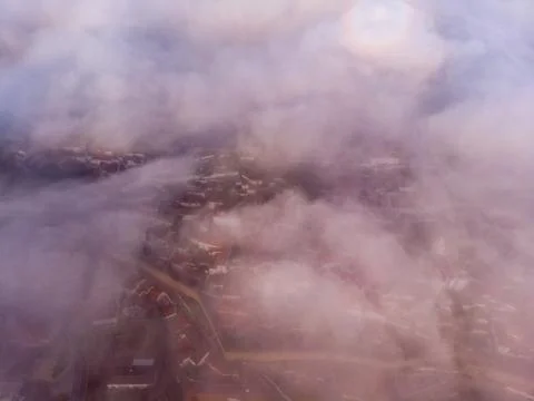 Upper view of red roofs of small city near river among hills against blue sky Stock Photos