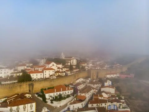 Upper view of red roofs of small city near river among hills against blue sky Stock Photos