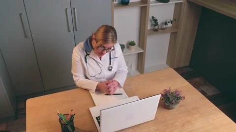 Upper view video of a caucasian blonde doctor talking online on laptop with the Stock Footage 147202224