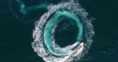 Upper view white motorboat sails making foamy circles on deep blue sea surface Stock Footage 90917843