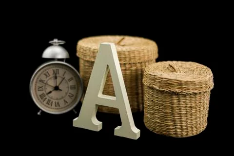 A uppercase with a set of two wicker baskets and a vintage alarm clock Stock Photos