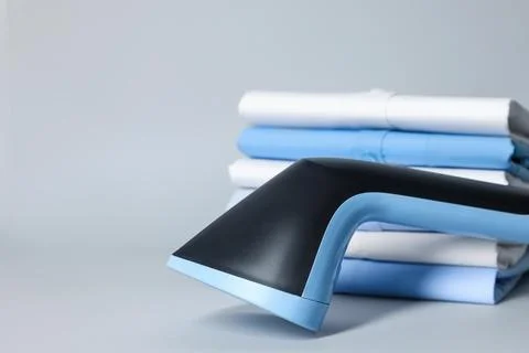 Upright steamer and stack of folded clothes on grey background, closeup. Sp.. 写真素材