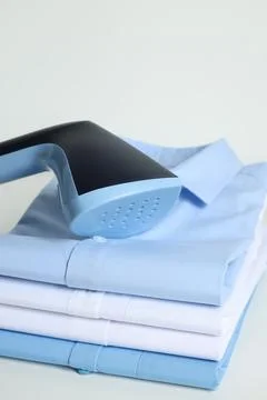 Upright steamer and stack of folded shirts on white table, closeup Foto stock