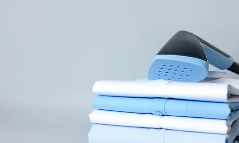 Upright steamer and stack of folded clothes on grey background, closeup. Sp.. 写真素材