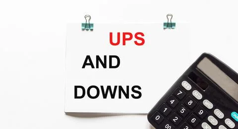 Ups and downs, the text is written on a white background, a calculator lies n 库存照片