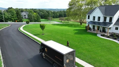 UPS delivery man returning to United Parcel Service branded truck after Stock Footage 253175527