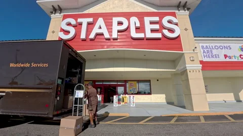 A UPS driver loads boxes in front of Staples retail store Stock Footage 344191095