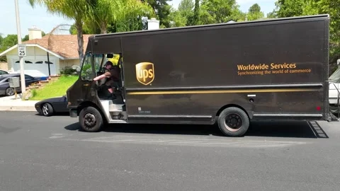UPS (United Parcel Service) driver and delivery trucks. Residential delivery  Stock Footage 246330391