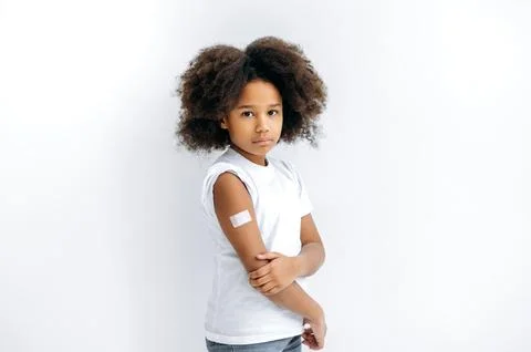 Upset African American curly haired little girl, with a band-aid on her shoulder Stock-Fotos