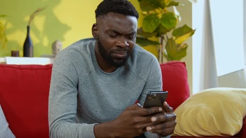 Upset african man receiving bad news on smartphone going crazy of internet Stock Footage