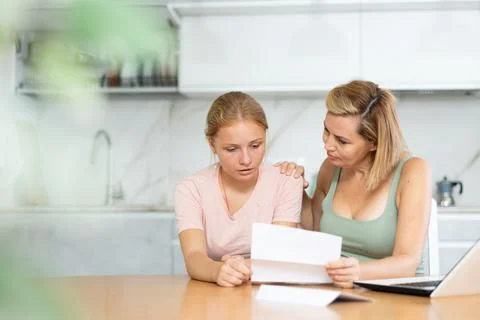 Upset and distressed mother and teenager daughter reads letter and learns Stock Photos