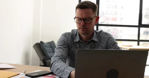 Upset annoyed man working on laptop while sitting in office Stock Footage 239453401