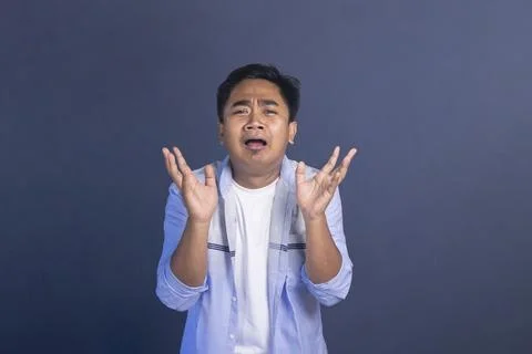 Upset Asian man with a sad expression holding his hands up in confusion or .. Stock Photos
