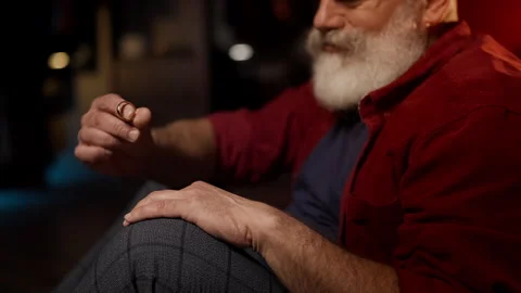 Upset bearded man in his 50s holds wedding ring, thinking about separation Stock Footage 342520604