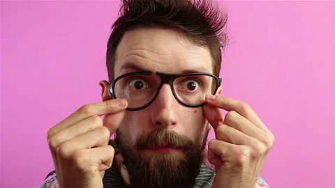 Upset bearded  man using broken glasses on pink bakground Stock Footage 169748778