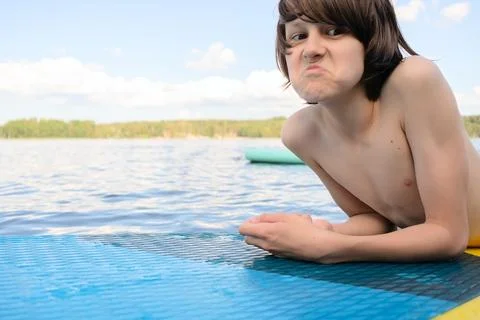 Upset Boy Lying on SUP Board with Pouting Face Foto stock