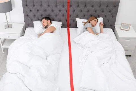 Upset couple with relationship problems lying separately in bed at home Stock Photos