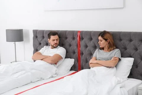 Upset couple with relationship problems lying separately in bed at home Stock Photos