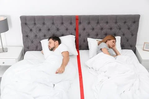 Upset couple with relationship problems lying separately in bed at home Stock Photos