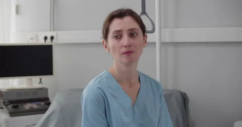 Upset crying female nurse sitting on empty hospital bed Stock Footage