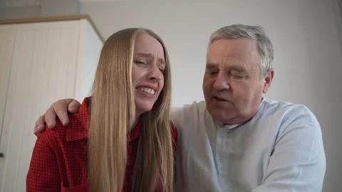 Upset daughter crying while sharing reasons for distress with her father, who Stock Footage 303646478
