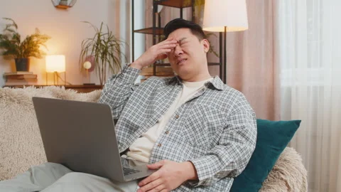 Upset displeased Chinese man using laptop computer reading bad news sitting on Stock Footage 297021422
