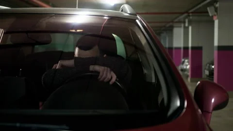 Upset driver lying down on the car wheel. Bearded man in a bad moon sitting in Stock Footage 232884624