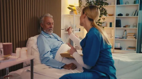 Upset elderly man refusing to eat breakfast brought by nurse, loss of appetite Stock Footage 279177645
