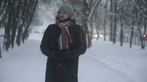 Upset freezing man walks through city in snow. 库存影片 257243557
