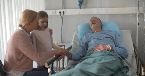 Upset grandmother and granddaughter visiting dying patient in hospital. Stock Photos