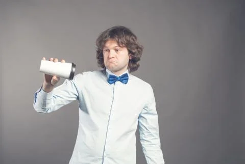 Upset guy with sad expression holding disposable paper cup of coffee upside down Stock Photos