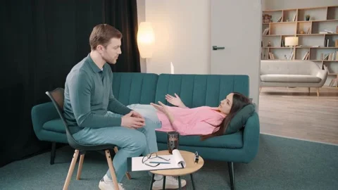Upset lady lying on sofa and talking with psychologist at therapy session Video stock 236243284