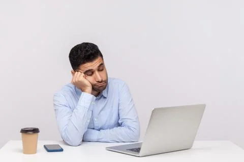 Upset lazy inefficient man employee sitting office workplace, looking at lapt Stock Photos