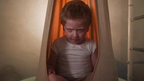 Upset little boy ready to cry sitting in orange hammock Stock Footage 243307708