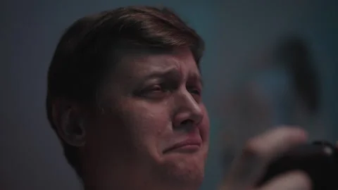 Upset losing gamer crying while holding gamepad, showcasing deep sadness and Stock Footage 317166874