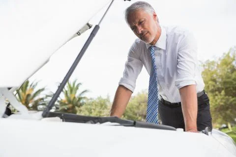 Upset man checking his car engine after breaking down Stock Photos