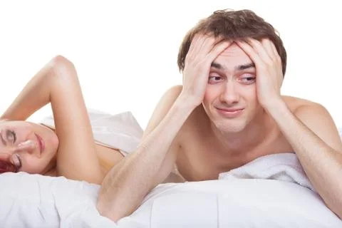 Upset man having problem on the bed with his wife on white background Stock Photos