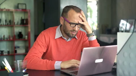 Upset man having problems during work on laptop at home 스톡 동영상 87815333