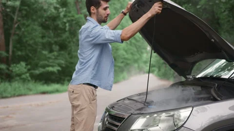 Upset man opens the hood of his car, the engine is smoking, calling by smartphon Stock Footage 278012938