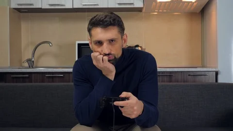Upset man is sitting on the couch playing video game on console and losing Stock Footage 121841948