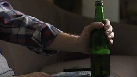Upset man sitting on sofa, drinking beer and thinking about problems, failure Stock Footage 86779242