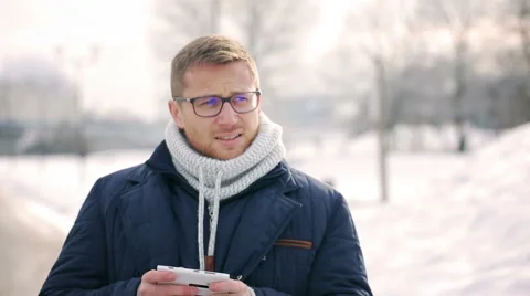 Upset man walking in the park at winter time and using smartphone Видео 46867681