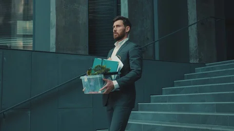 Upset office worker young man walking on stairs with box of personal stuff lose Stock Footage 129462921