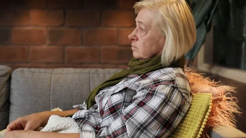 Upset old lady lying on sofa, measuring temperature in living room. Grandmother Stock Footage 92279925