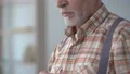 Upset old man buttoning up shirt, sighing and remembering wife, loneliness 4k or 4k+ Resolution