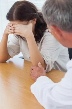 Upset patient crying while doctor comforting her Stock Photos