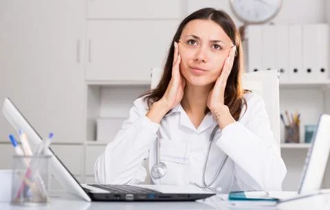 Upset practicioner girl is working with documents and laptop Stock Photos
