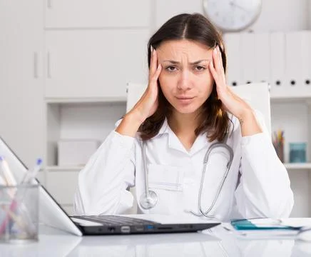 Upset practicioner girl is working with documents and laptop Stock Photos