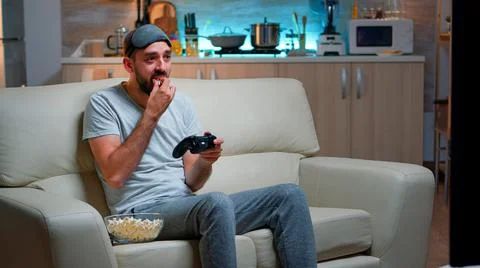 Upset pro gamer sitting on couch and playing soccer videogames Stock Photos