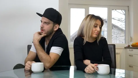 Upset sad couple drinking coffee after a fight sitting in the kitchen at home Stock Footage 72896997